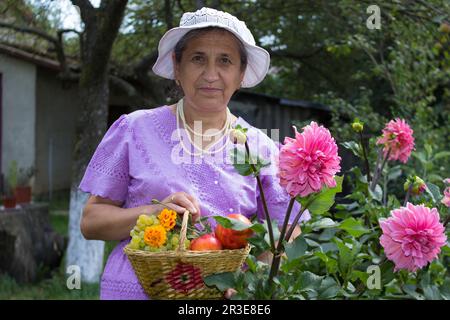 femme âgée en chapeau avec panier de fruits entre les mains Banque D'Images
