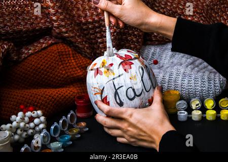 BRICOLAGE. Faites-le vous-même. Une femme peint des décorations d'action de grâce sur la citrouille d'orange pour Halloween. Récolte d'automne. Banque D'Images