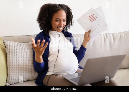 Joyeuse femme noire millénaire en vêtements de maison avec grand ventre aime la grossesse dans les écouteurs Banque D'Images