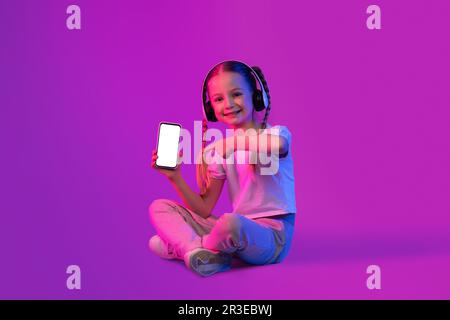 Joyeux enfant adorable fille montrant une belle application mobile pour les enfants Banque D'Images