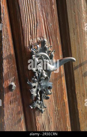 Photo prise à Bratislava. Sur la photo, une poignée de porte faite avec art sur une ancienne porte en bois. Banque D'Images