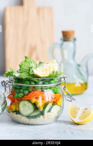 Bol en verre avec légumes frais crus et gruaux couscous. Préparation de repas sains - photos de préparation de recettes. Plats végétariens sains Banque D'Images