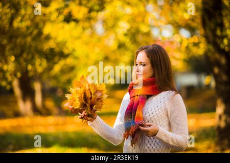 Jolie femme souriante tenant des feuilles d'érable d'automne Banque D'Images