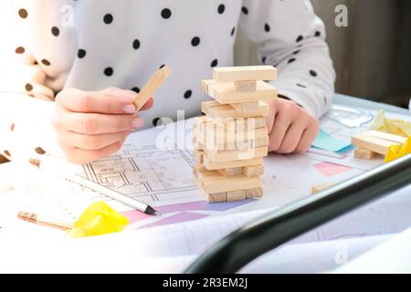 Architecte designer intérieur créatif travail main jouant un jeu de bois de bloc sur le bureau plan architectural de la maison, un PAL de couleur Banque D'Images