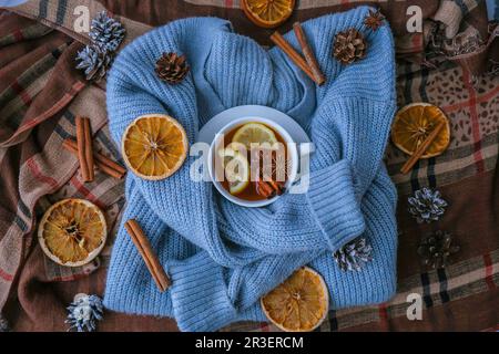 Chandail bleu et tasse de thé chaud avec bâtonnets de cannelle au citron et étoile anis. Séchez les tranches d'orange-agrumes et les cônes. Chaud hiver coc Banque D'Images