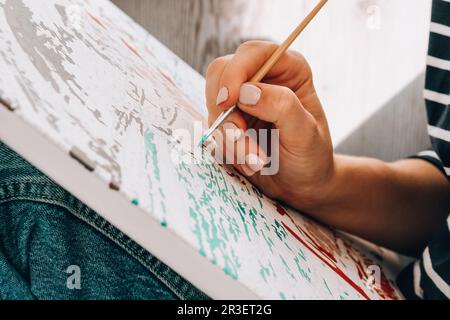 Peinture sur toile par numéros et pots de peinture numérotés. Femme tire avec une brosse. Passe-temps créatif. Peinture pour débutants. Leis Banque D'Images