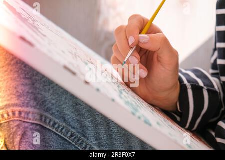 Peinture sur toile par numéros et pots de peinture numérotés. Femme tire avec une brosse. Passe-temps créatif. Peinture pour débutants. Leis Banque D'Images