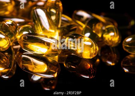 Gros plan de la capsule de gel Omega 3 sur fond noir réfléchissant Banque D'Images