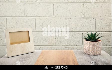 plan de concept de blanc cadre photo en bois vide sur bureau en bois avec usine de maison et mur de brique en arrière-plan Banque D'Images