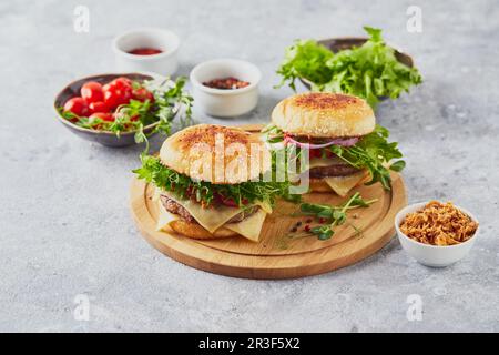 Deux hamburgers avec escalope de veau et herbes sur planche à découper en bois Banque D'Images