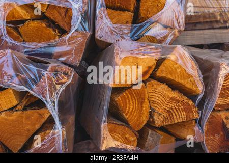 Bois de chauffage sec dans des sacs en plastique dans le centre du jardin. Bois dur à vendre Banque D'Images