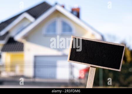 Panneau noir vierge contre le nouveau bâtiment de maison modèle de maquette vide étiquette de panneau noir Maison à louer. Maison à vendre. Se connecter f Banque D'Images