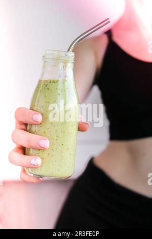 Jeune femme blonde millénelle boit du smoothie végétalien Detox. Femme faisant des exercices de yoga à la maison. Manger propre, perte de poids, Banque D'Images