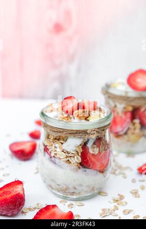 Petit déjeuner sain. Flocons d'avoine Granola au yaourt grec et aux noix muesli aux fraises en pots sur fond clair. Végétalien, végétarien Banque D'Images