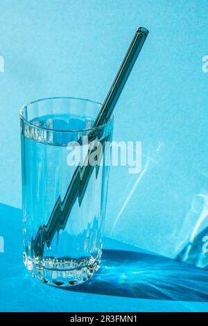Pailles en verre réutilisables en verre avec eau sur fond bleu ensemble de pailles écologiques avec brosse de nettoyage. Aucun gaspillage, pl Banque D'Images