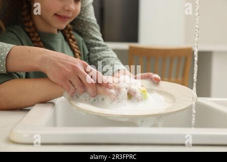 Plaque de lavage de la mère et de la fille au-dessus de l'évier à l'intérieur, gros plan Banque D'Images