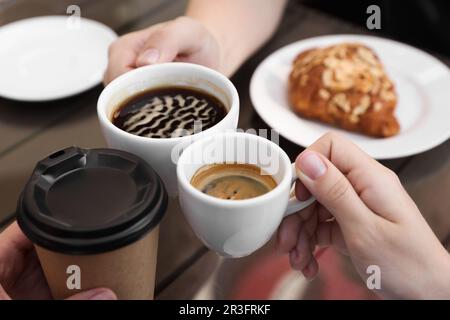 Des amis buvant du café à une table en bois dans un café extérieur, à proximité Banque D'Images