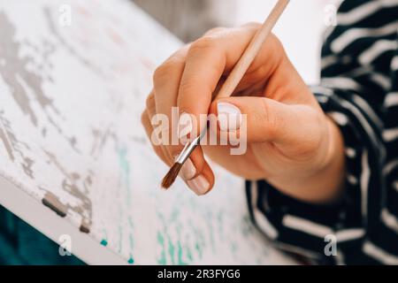 Peinture sur toile par numéros et pots de peinture numérotés. Femme tire avec une brosse. Passe-temps créatif. Peinture pour débutants. Leis Banque D'Images