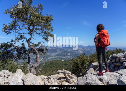 Femme avec sac à dos bénéficiant de la vue sur les montagnes tramuntana et l'ermitage de Maristela, son Ferra, Esporles, Iles Baléares, Espagne. Banque D'Images