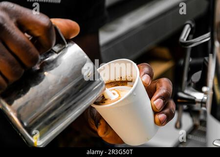 Café africain Barista verser une forme de coeur avec de la mousse de lait Banque D'Images