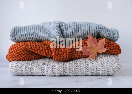 Pile de chandail chaud en maille confortable avec feuille d'érable d'automne. Chandails de style rétro. Couleurs orange et bleu. Confortable salle de détente Banque D'Images