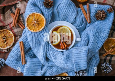 Chandail bleu et tasse de thé chaud avec bâtonnets de cannelle au citron et étoile anis. Séchez les tranches d'orange-agrumes et les cônes. Chaud hiver coc Banque D'Images