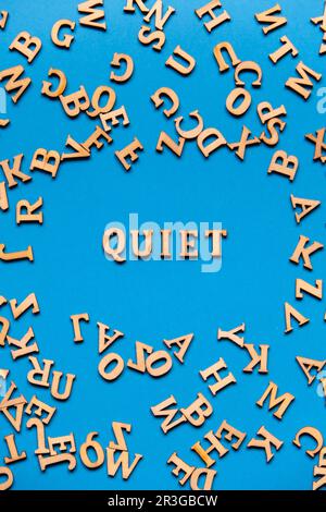 Mot QUIET fait de lettres en bois sur fond bleu clair. Concept de citations de mots de motivation. Banque D'Images