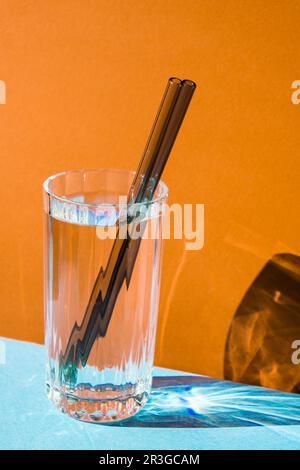 Pailles en verre réutilisables en verre avec eau sur fond coloré ensemble de pailles écologiques avec brosse de nettoyage. Aucun gaspillage Banque D'Images