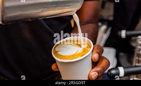 Café africain Barista verser une forme de coeur avec de la mousse de lait Banque D'Images