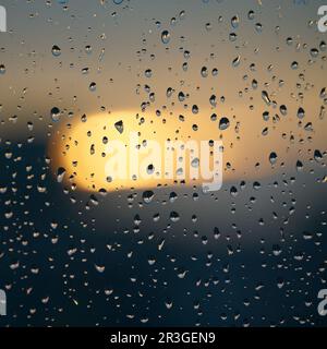 Gouttes de pluie sur une fenêtre après une pluie au coucher du soleil Banque D'Images