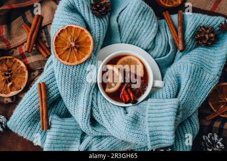 Chandail bleu et tasse de thé chaud avec bâtonnets de cannelle au citron et étoile anis. Séchez les tranches d'orange-agrumes et les cônes. Chaud hiver coc Banque D'Images