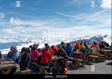 Les gens qui apprécient les alpes tout en buvant et en mangeant sur des tables de pique-nique dans un restaurant au sommet du glacier 3000 en Suisse. Banque D'Images