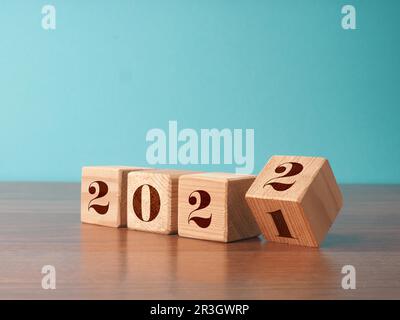 Des cubes en bois à retourner avec les numéros de l'année 2021 et 2022, concept du nouvel an, période de Noël saisonnière Banque D'Images