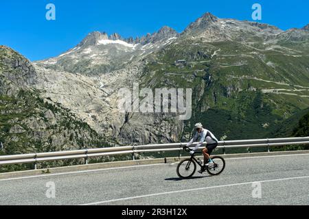 Cyclistes sur la descente du col de Furka, en arrière-plan le lit libre de glace du glacier du Rhône, route de Furkapas près de Gletsch, Valais, Suisse Banque D'Images