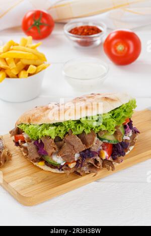 Doner Kebab Doner Kebap repas rapide dans le menu de pain pita avec des frites sur le plan de la cuisine format portrait Banque D'Images