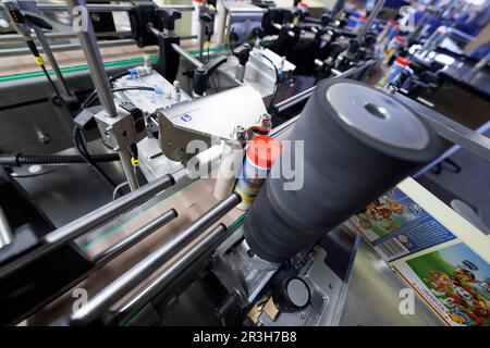 PRODUCTION - 19 avril 2023, Baden-Württemberg, Tübingen: Dans la ligne de production, une machine à étiqueter applique des étiquettes sur les boîtes en plastique. Pustefix de Tübingen, connu pour ses suds à bulles de savon dans une boîte en plastique bleu avec un ours en peluche jaune, célèbre son 75th anniversaire en 2023. Photo: Julian Rettig/dpa Banque D'Images