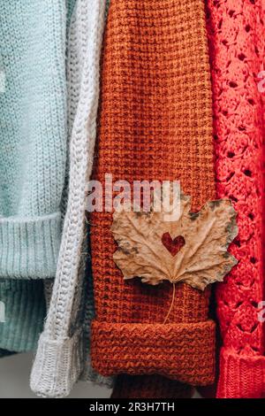 Concept d'automne. Feuille d'érable en forme de coeur sur un pull chaud et confortable. Pulls tricotés en laine et mohair. Style hygge Banque D'Images