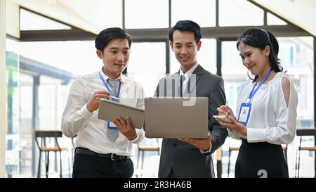 Groupe d'hommes d'affaires asiatiques professionnels partageant leurs idées, examinant un projet sur ordinateur portable et travaillant ensemble au bureau. Banque D'Images