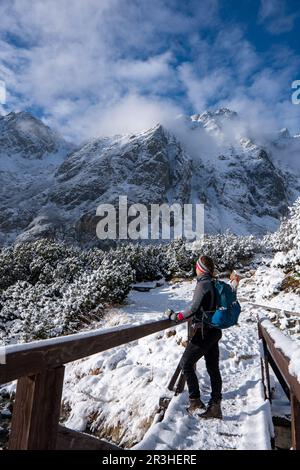 Femme de randonnée debout sur le pont et regarde autour, en admirant le paysage de montagne d'hiver. Bonne touriste en hiver. Tatras élevé, 1987 mètres plus haut Banque D'Images