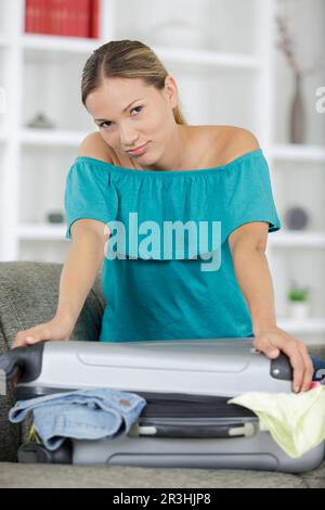 Femme luttant pour fermer suitcase Banque D'Images