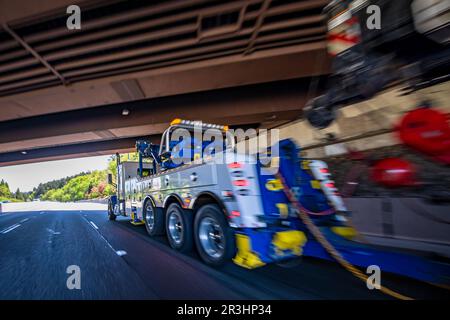 Puissant camion semi-remorque bleu de grande taille avec flèche de levage et treuil de remorquage grue industrielle cassée conduisant sur la large route un Banque D'Images