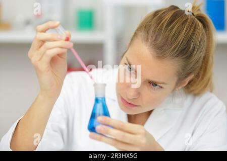 Jeune femme technicien utilise une pipette dans un laboratoire chimique Banque D'Images