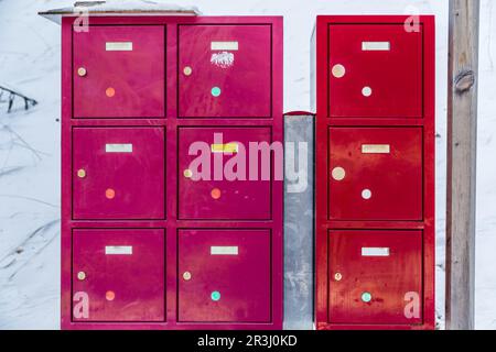 Boîtes aux lettres métalliques rouge et fuchsia dans la neige Banque D'Images