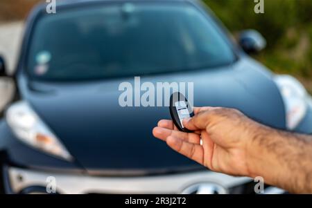 Tenez une télécommande de voiture avec les boutons de verrouillage et de déverrouillage. mise au point sélective avec arrière-plan flou Banque D'Images