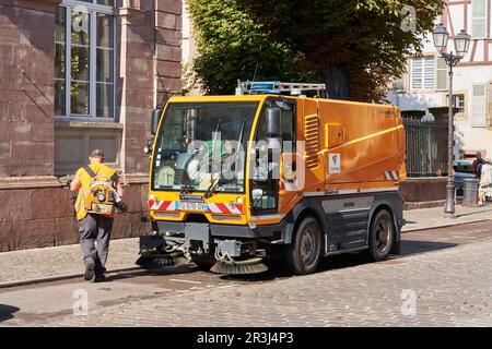 Ouvrier nettoyant la rue avec un balai dans la vieille ville de Colmar en France Banque D'Images