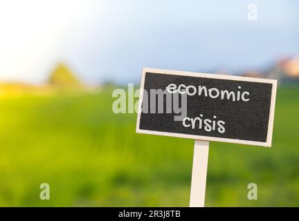 Panneau d'étiquette d'information en bois avec texte CRISE ÉCONOMIQUE contre l'agriculture désamorcée message de terrain. Faim dans le monde, inflation, h Banque D'Images