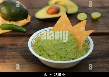 Délicieux guacamole fait d'avocats avec nachos sur table en bois Banque D'Images