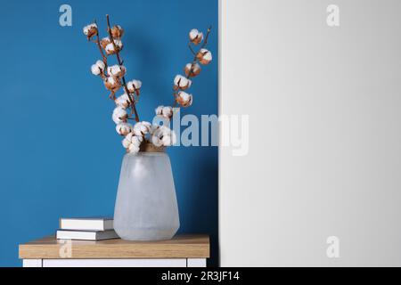 Branches en coton avec fleurs moelleuses dans vase et livres sur table en bois à l'intérieur. Espace pour le texte Banque D'Images