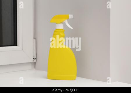 Pulvérisateur jaune de produit de nettoyage sur le seuil de la fenêtre à l'intérieur Banque D'Images