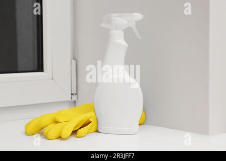 Vaporiser un flacon de produit nettoyant et des gants en caoutchouc sur le rebord de la fenêtre à l'intérieur Banque D'Images